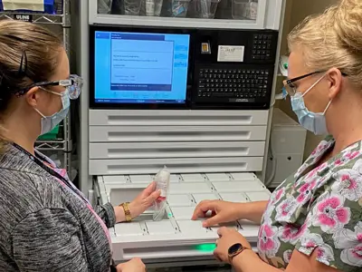 Pharmacy and nursing staff with an automated medication dispensing cabinet.