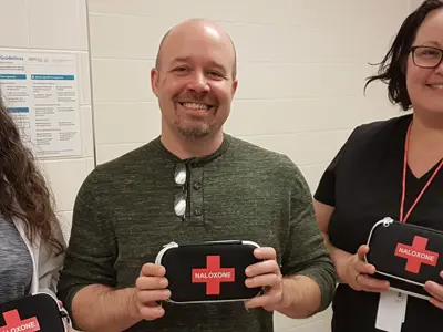 Three staff holding naloxone kits