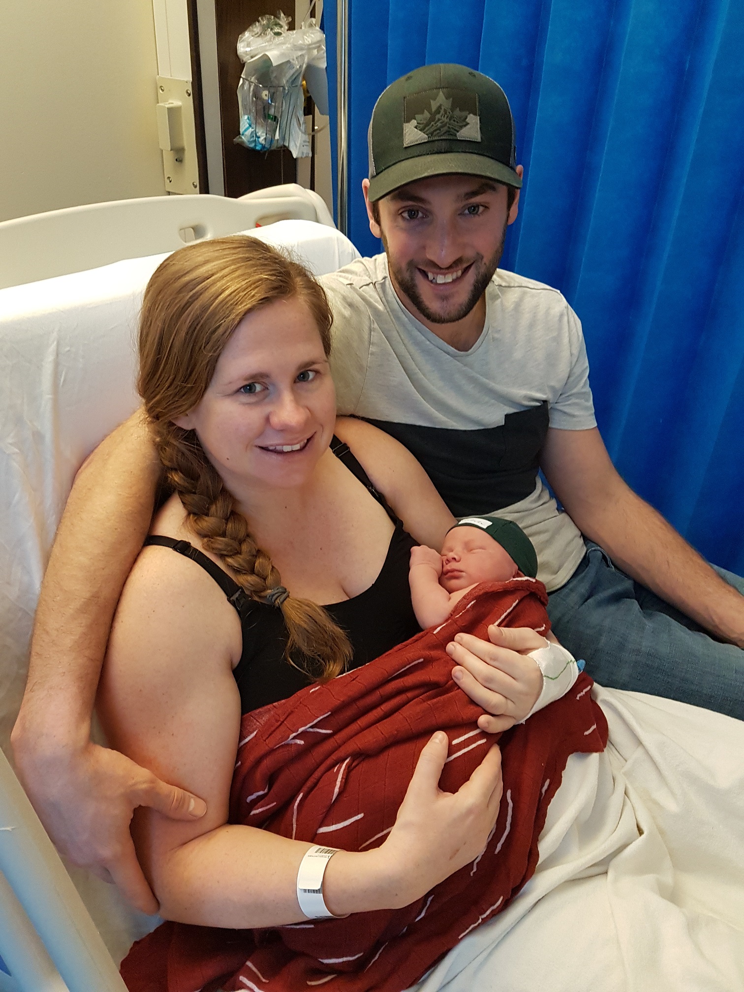 Woman holding newborn baby, sitting beside man