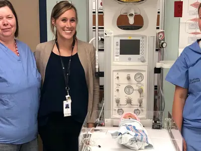 Staff standing beside the new infant warmer