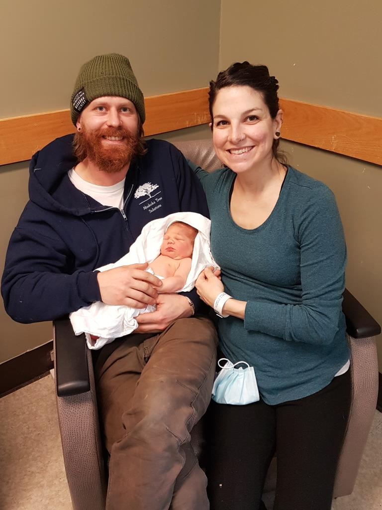 Man holding newborn baby sitting beside woman